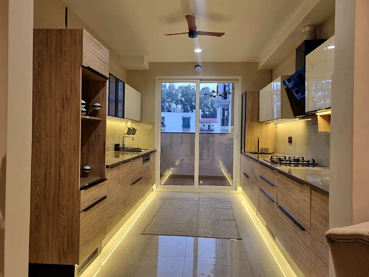 Modular kitchen with LED under-cabinet lighting and wood finish in smart home Zirakpur flat